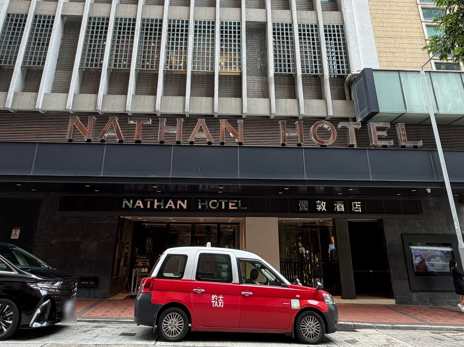 昼の Nathan Hotel の入口。NATHAN HOTEL と彌敦酒店の看板